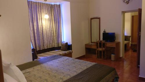 a bedroom with a bed and a tv and a mirror at Sai Towers in Puttaparthi