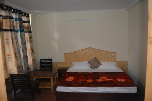マナリにあるHimalaya Cottageのベッドルーム1室(ベッド1台、テーブル、椅子付)