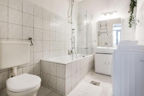 a white bathroom with a toilet and a tub and a sink at W2 Synagogue Apartment in Budapest