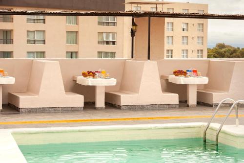 uma piscina com mesas e cadeiras ao lado de um edifício em Gran Hotel San Luis em San Luis