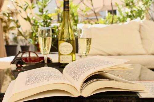 un libro abierto sobre una mesa con copas de vino en Hotel Le Charleston, en Le Mans