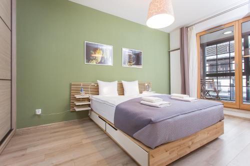 a bedroom with a bed and a green wall at InPoint Downtown Apartments near Old Town in Krakow