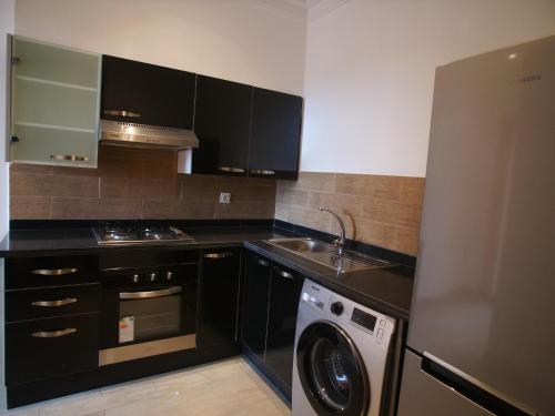 Una cocina con gabinetes negros y lavadora y lavavajillas. en Jnane Gueliz, en Marrakech