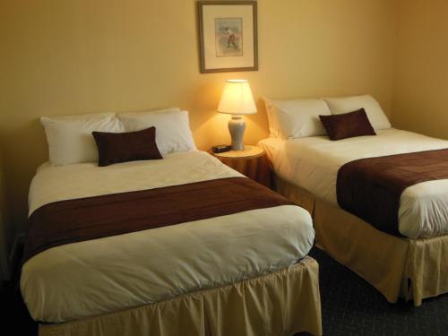 a hotel room with two beds and a lamp at Beau Rivage Golf and Resort in Wilmington