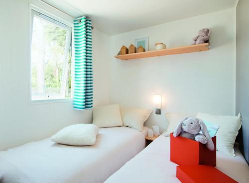 une chambre avec deux lits et un éléphant farci dans une boîte dans l'établissement Camping Le Bois Verdon, à Saint-Jean-de-Monts