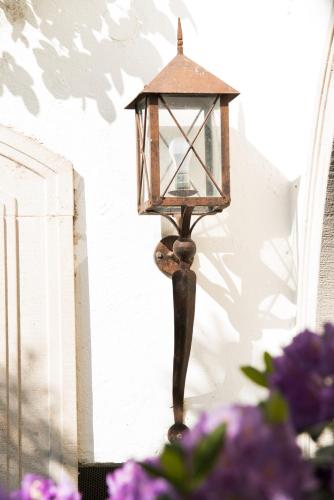 a lantern hanging on a wall with purple flowers at Ansitz Wendelstein in Appiano sulla Strada del Vino