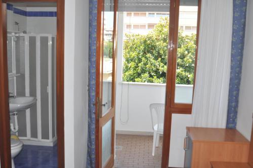 a bathroom with a toilet and a window at Hotel Villa Candia in Lignano Sabbiadoro