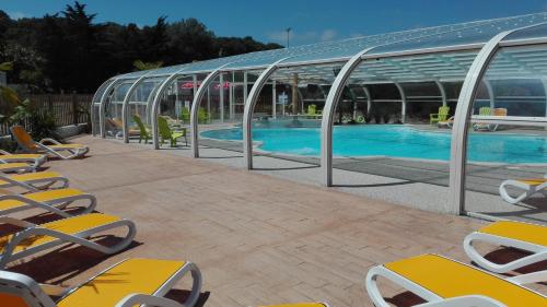une piscine avec des chaises longues et un bâtiment dans l'établissement Camping Le Bois Verdon, à Saint-Jean-de-Monts