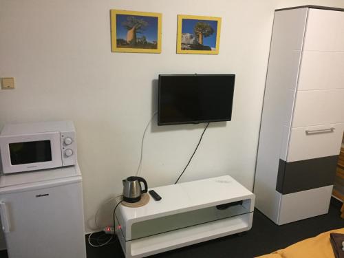 a room with a microwave and a tv on a wall at Penzion Eden Turnov in Turnov