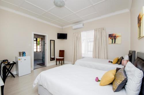 a bedroom with two white beds and a television at Walmer Villiers Self Catering in Port Elizabeth