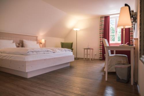 エッシンクにあるLandhotel - Hotel & Brauereigasthof Schneiderのベッドとデスクが備わるホテルルームです。