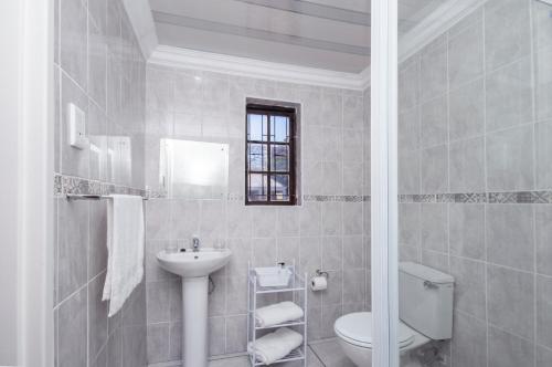 a white bathroom with a toilet and a sink at Walmer Villiers Self Catering in Port Elizabeth
