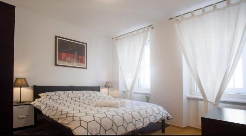 una camera da letto con un letto con lenzuola bianche e finestre di Apartments S&A a Zagabria