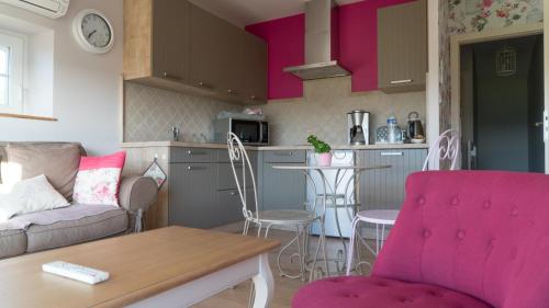 un soggiorno con divano e una cucina con armadietti rosa di Le Petit Nid*** a Amance