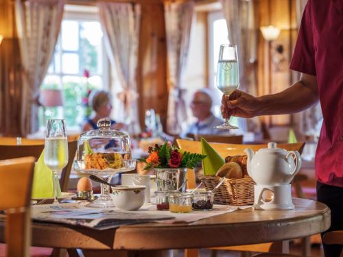 a man holding a wine glass over a table with food at Romantik Hotel Knippschild in Rüthen