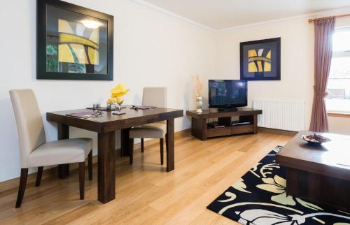 a living room with a dining room table and a television at The Claymore Guest House in Pitlochry