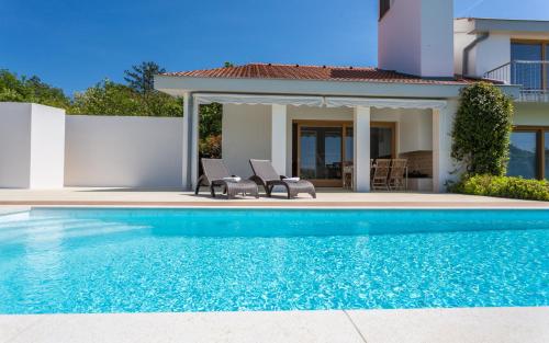 a swimming pool with two chairs and a house at Casa Vidmar in Klimno