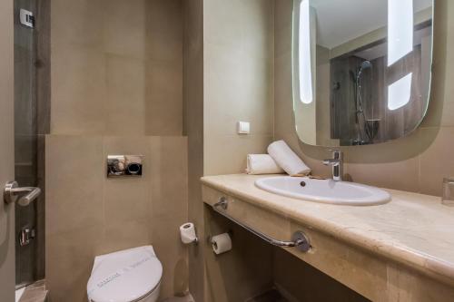 a bathroom with a sink and a toilet and a mirror at Ibis Marrakech Centre Gare in Marrakech