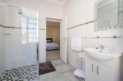 a white bathroom with a sink and a shower at Walmer Villiers Self Catering in Port Elizabeth