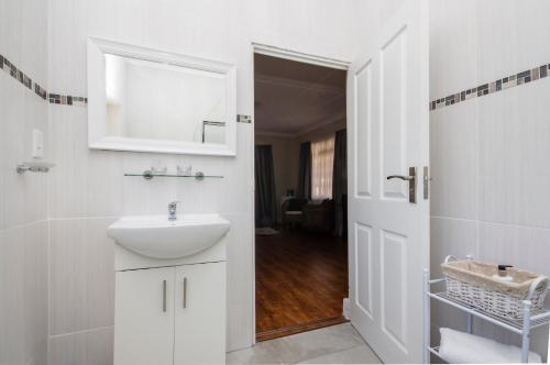 a white bathroom with a sink and a mirror at Walmer Villiers Self Catering in Port Elizabeth