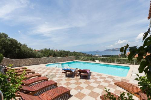 a swimming pool with lounge chairs and a swimming pool at Apartments Carol Royal in Cavtat