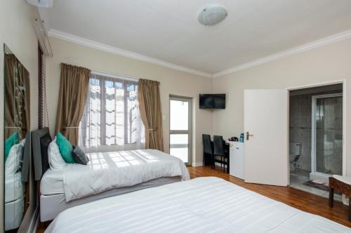 a bedroom with two white beds and a window at Walmer Villiers Self Catering in Port Elizabeth