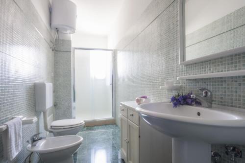 a white bathroom with a sink and a toilet at Attico Saker in Racale