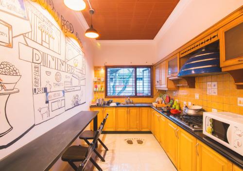 a kitchen with a counter with drawings on the wall at Zostel Mysore in Mysore
