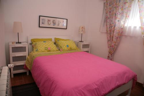 a bedroom with a pink bed with yellow pillows at Stella's House in Nazaré
