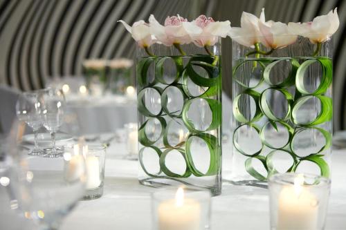 a table with two vases with flowers and candles at Porto Palace Hotel Thessaloniki in Thessaloniki