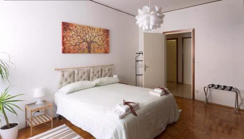 Un dormitorio con una cama blanca y una pintura en la pared en Guest House Cuore del Friuli en Udine