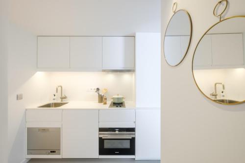 a white kitchen with a sink and a mirror at 1bd apartment with garden Brugmann area in Brussels