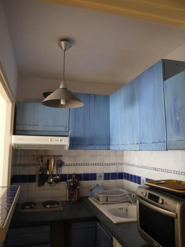 - une cuisine avec des placards bleus et un évier blanc dans l'établissement Résidence Ciel de Fabron, à Nice