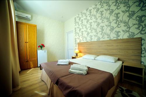 a bedroom with a bed with two towels on it at Hotel Dombay in Gelendzhik