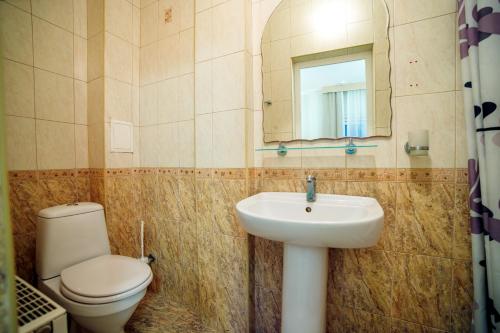 a bathroom with a toilet and a sink and a mirror at Hotel Dombay in Gelendzhik