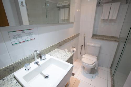 a white bathroom with a sink and a toilet at Catussaba Business Hotel in Salvador