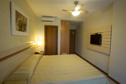 a large bed in a room with a ceiling fan at Catussaba Business Hotel in Salvador