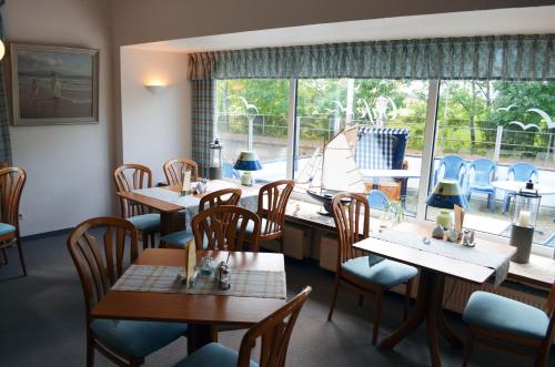 a restaurant with tables and chairs and a large window at Hotel das Möwenstübchen in Wremen