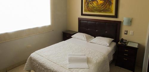 1 dormitorio con 1 cama con 2 toallas en Rivera del Rio Hotel, en Piura