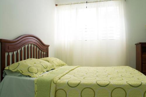 1 cama con manta verde y ventana en The Room Cozy-Nest, en Santiago de los Caballeros