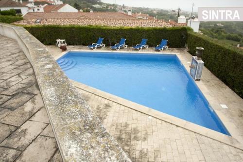 a large swimming pool with blue chairs at Heaven in the Sintra Forest - with pool in Sintra
