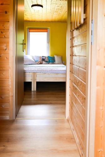 a dog laying on a bed in a room with a window at Domek nad jeziorem, Kalinówka w Olchowcu, Solina in Olchowiec