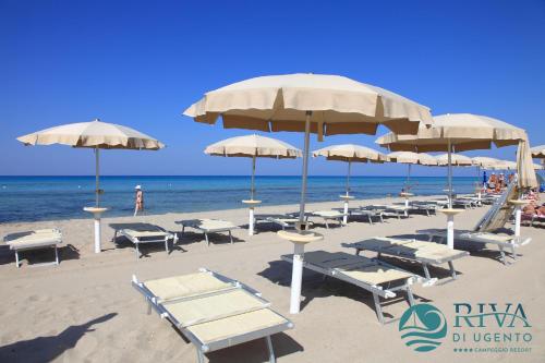 a beach with a bunch of chairs and umbrellas at Riva di Ugento Beach Camping Resort in Ugento