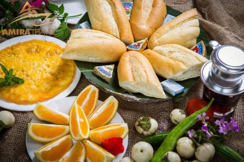 a table topped with plates of bread and orange slices at Tuan Nam Homestay in Ninh Binh