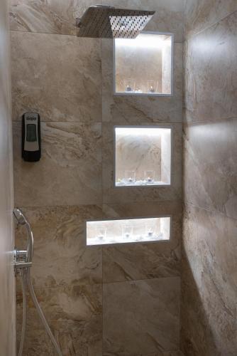 a bathroom with a shower with three shelves in it at Stelios Gardens in Malia