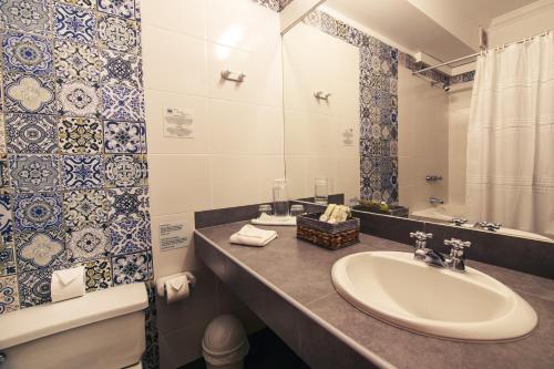 a bathroom with a sink, mirror, and bathtub at Hotel Antigua Miraflores in Lima