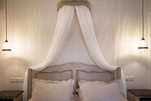 a bed with a canopy with white pillows at Stelios Gardens in Malia