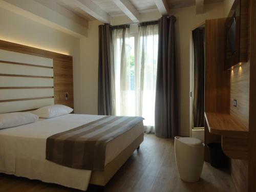 um quarto de hotel com uma cama e uma grande janela em Bio Suites PACINOTTI em Bardolino