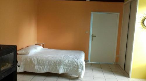 een slaapkamer met een wit bed en een oranje muur bij Location 24 heures du Mans in Louplande
