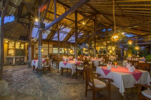 a restaurant with tables and chairs in a building at Tamukami Hotel in Sanur
